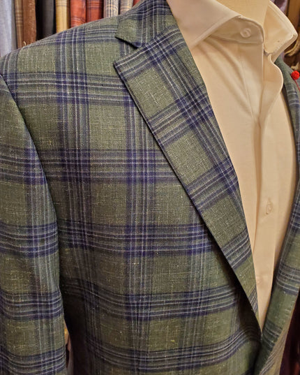 Green plaid fabric with a beige shirt underneath, on a wooden surface.