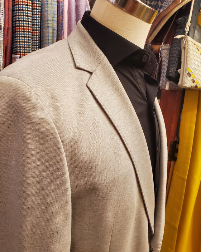 Close-up of a beige suit jacket on a fabric-covered surface with colorful patterns.