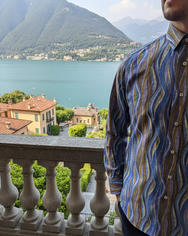 Folded patterned shirt on a wooden surface with other shirts in the background
